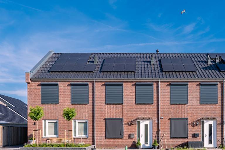 Newly build houses with solar panels attached on the roof against a sunny sky Close up of new building with black solar panels. Zonnepanelen, Zonne energie, Translation: Solar panel, , Sun Energy.