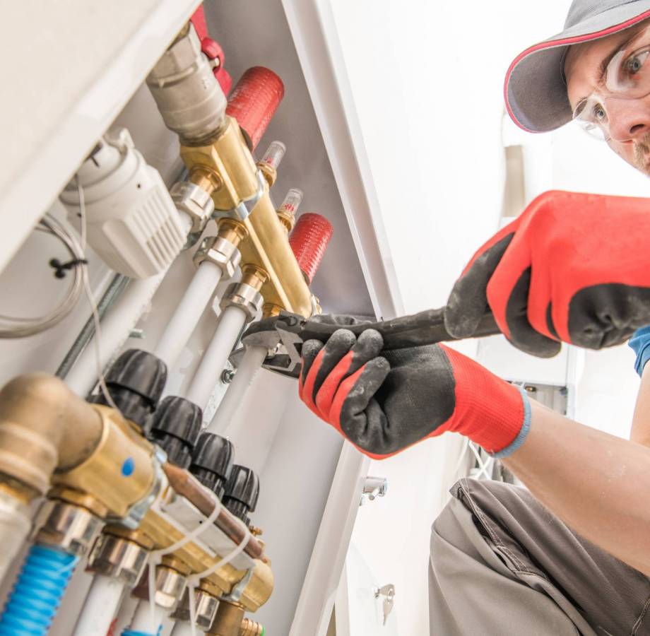 Residential House Floor Heating Valves Adjustment. Plumbing and Heating Technician at Work.