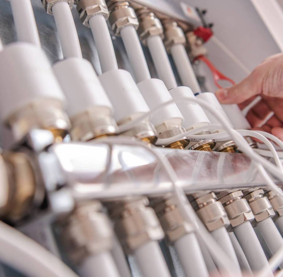 Modern Home Water Heating Valves Adjusting by Caucasian Men. Row of Valves Close Up.